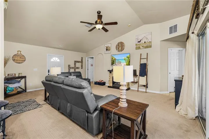 Living room featuring light carpet, a ceiling fan, and high vaulted ceiling