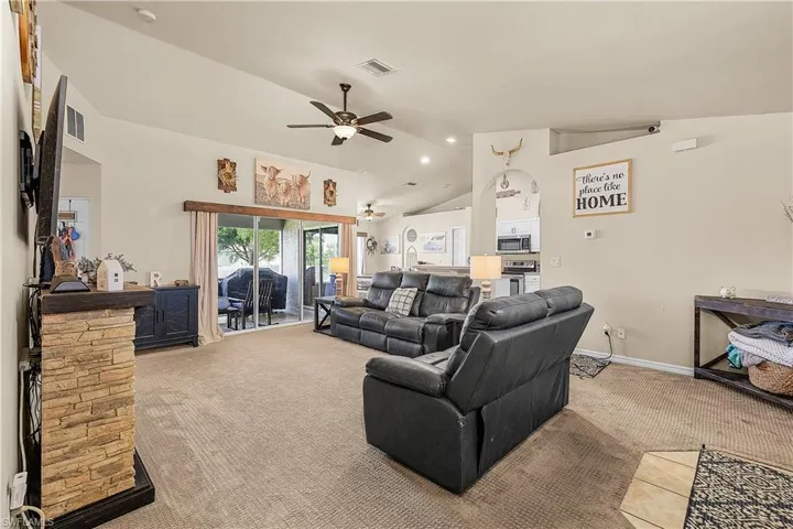 Kitchen featuring stainless steel appliances, white cabinetry, vaulted ceiling, and open floor plan