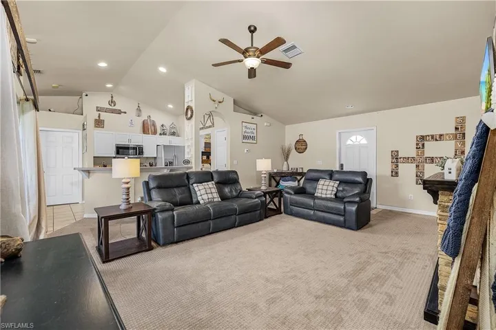 Living room featuring light carpet, a ceiling fan, high vaulted ceiling, and recessed lighting