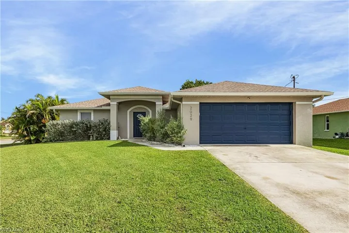 View of front facade with stucco siding, a front yard, concrete driveway, and a garage