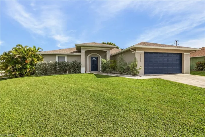 View of front of property with stucco siding, a front yard, concrete driveway, and a garage