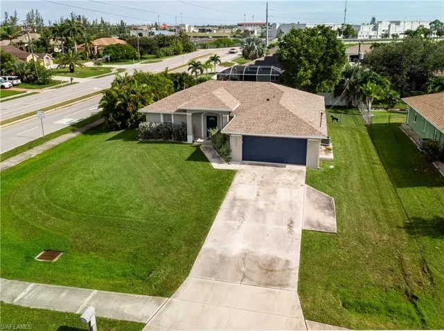 Ranch-style house with driveway, a garage, roof with shingles, and a front yard