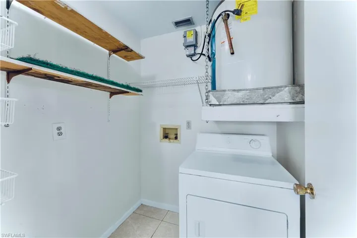 Laundry room featuring washer / dryer, light tile patterned flooring, and water heater