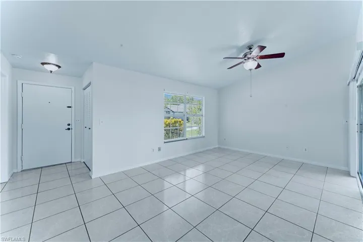 Spare room with ceiling fan, lofted ceiling, and light tile patterned flooring