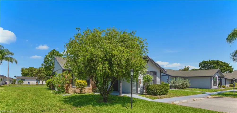 View of property hidden behind natural elements with a front yard