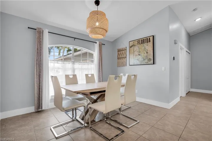 Dining area featuring light tile patterned flooring and vaulted ceiling