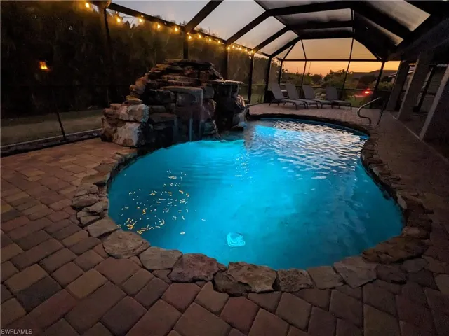 Outdoor pool featuring a sunroom, glass enclosure, and a patio area