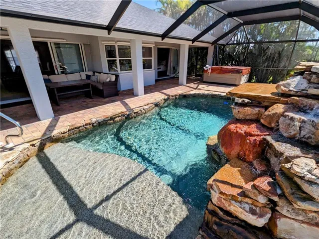 Swimming pool featuring a hot tub, a sunroom, a lanai, a patio area, and an outdoor hangout area