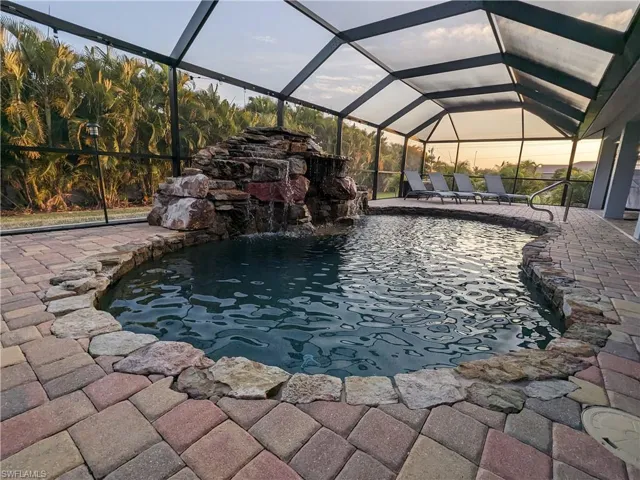 Pool at dusk featuring a sunroom, glass enclosure, and an outdoor pool