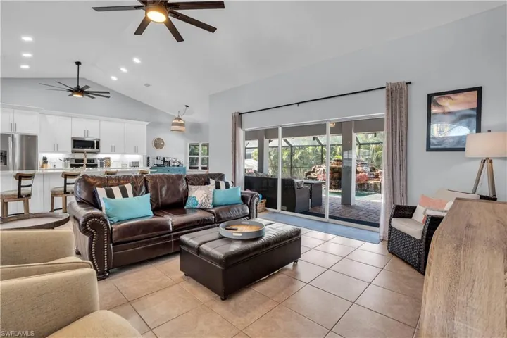 Living room featuring high vaulted ceiling, light tile patterned flooring, recessed lighting, and a ceiling fan