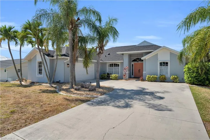 Ranch-style home featuring a front lawn, driveway, roof with shingles, and stucco siding