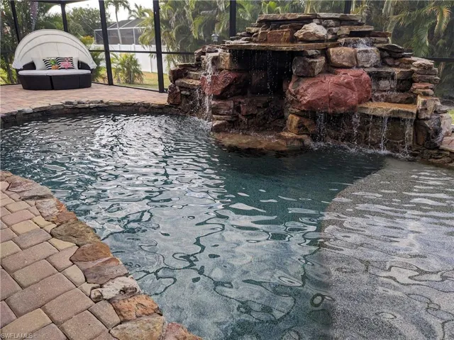 View of swimming pool featuring glass enclosure, a small pond, and a swimming pool