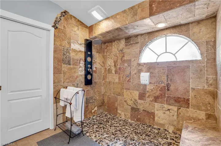 Bathroom with tiled shower, tile patterned flooring, and tile walls