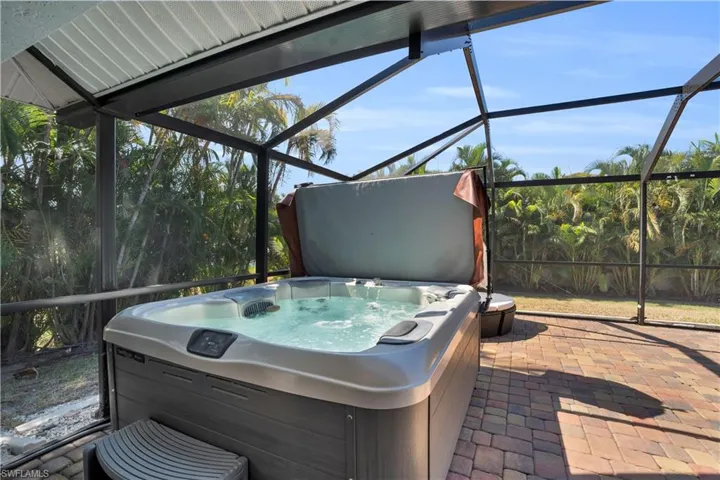 View of patio with glass enclosure, a hot tub, and a sunroom