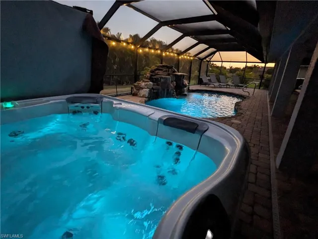 Swimming pool featuring an outdoor hot tub, a sunroom, a lanai, and a patio area