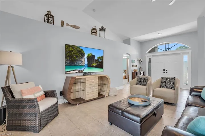 Living area with arched walkways, high vaulted ceiling, and tile patterned flooring