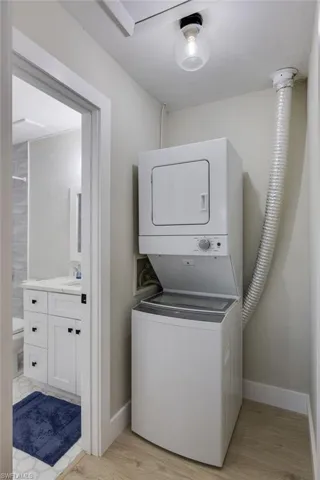 Laundry room featuring stacked washer and clothes dryer and light wood-type flooring