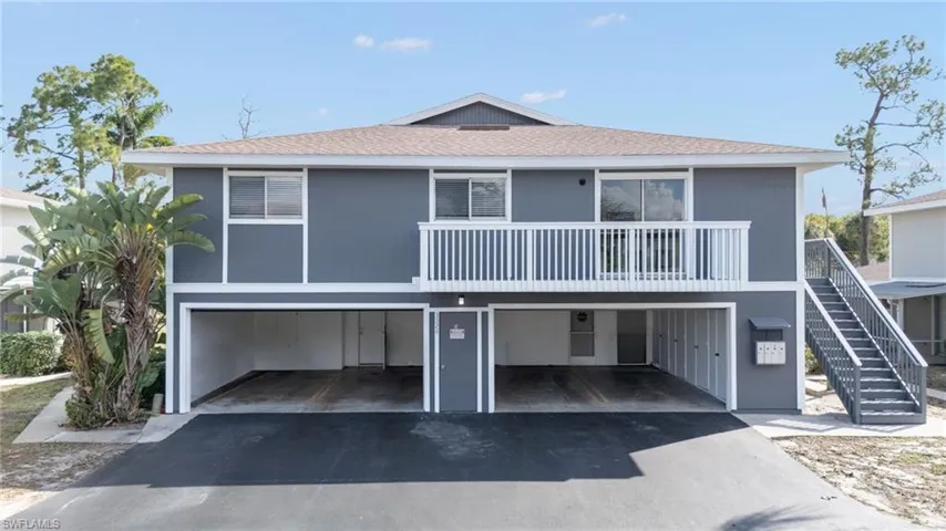 Coastal inspired home with roof with shingles, a carport, and asphalt driveway