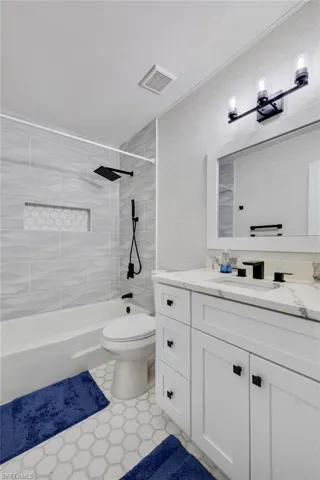 Bathroom with vanity, shower / bath combination, and a textured wall