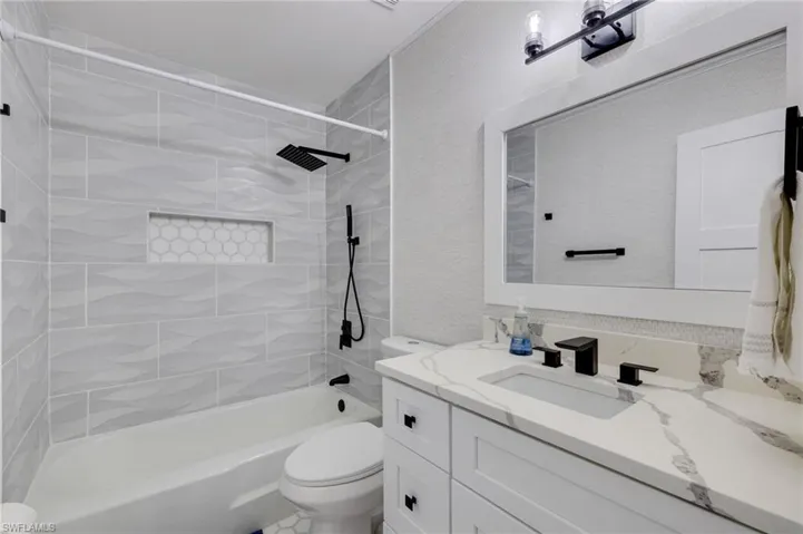 Full bath featuring vanity, washtub / shower combination, and a textured wall