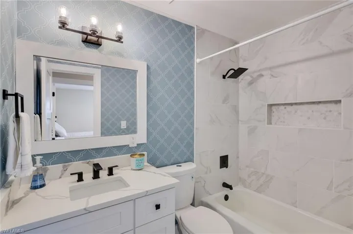 Full bath featuring vanity, tub / shower combination, wallpapered walls, and ensuite bath