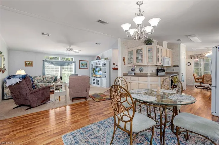 Dining space featuring ceiling fan with notable chandelier and light wood-type flooring