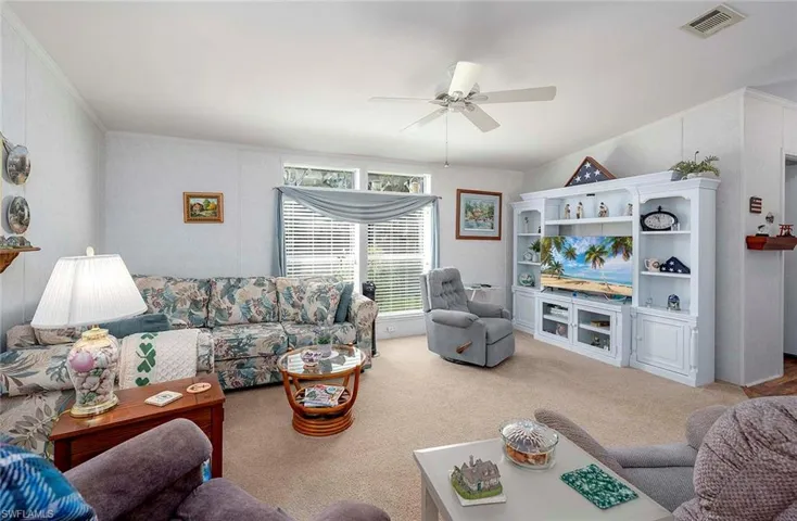 Living room with ceiling fan, carpet, and ornamental molding