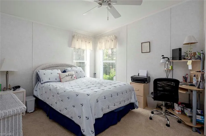 Carpeted bedroom with ceiling fan and ornamental molding