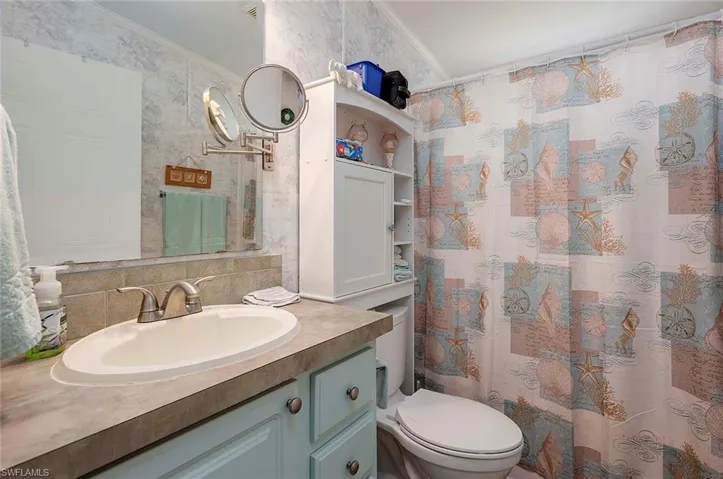 Bathroom featuring ornamental molding, toilet, backsplash, and vanity