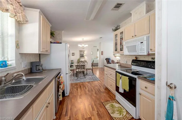 Kitchen featuring sink, a notable chandelier, light hardwood / wood-style flooring, decorative backsplash, and white appliances