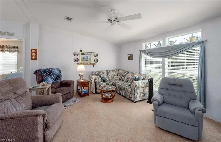 Carpeted living room featuring ceiling fan, ornamental molding, and a healthy amount of sunlight