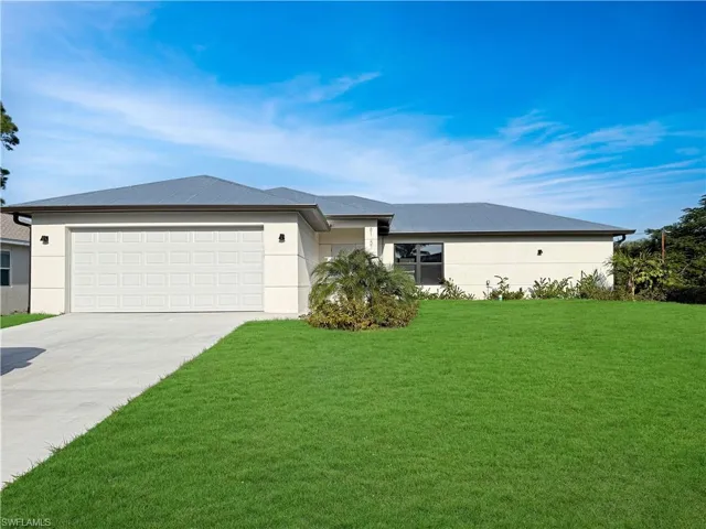 Prairie-style home with a front lawn, driveway, stucco siding, and an attached garage