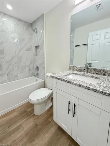 Full bath featuring shower / tub combination, vanity, and light wood finished floors
