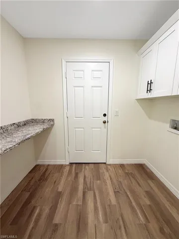Laundry area with dark wood-type flooring, cabinet space, and washer hookup