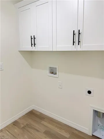 Laundry area featuring washer hookup, hookup for an electric dryer, light wood finished floors, and cabinet space