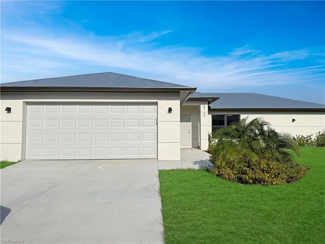 View of front of home with concrete driveway, a front yard, stucco siding, and a garage
