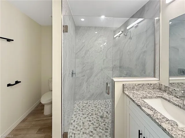 Full bathroom with a marble finish shower, wood tiled floors, vanity, and recessed lighting