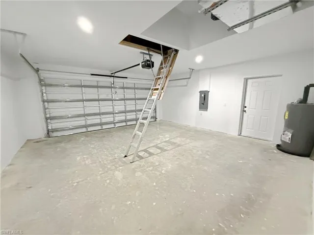 Garage with electric water heater, electric panel, and a garage door opener