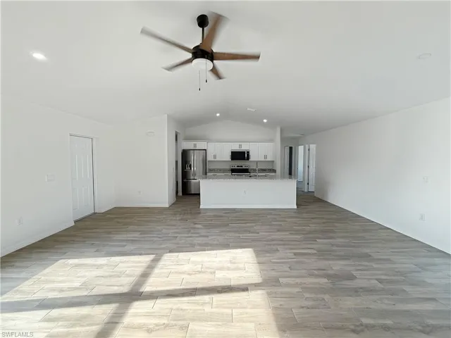 Unfurnished living room featuring lofted ceiling, light wood-type flooring, a ceiling fan, and recessed lighting