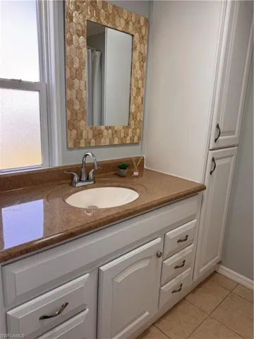 Master full bathroom with vanity, light tile patterned floors, and curtained shower