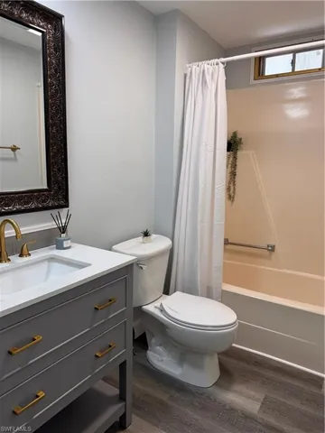Bathroom featuring dark wood-style flooring, vanity, and shower / tub combo with curtain