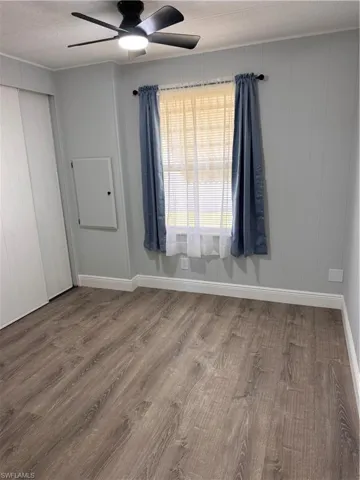 Unfurnished guest bedroom with laminate floors, a textured ceiling, a closet, and a ceiling fan