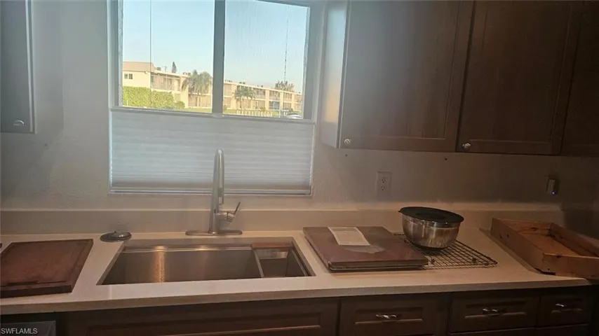 Kitchen with light countertops, ceiling fan, dark brown cabinets, and open floor plan