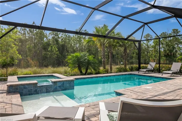 View of swimming pool with a patio, glass enclosure, and a pool with connected hot tub