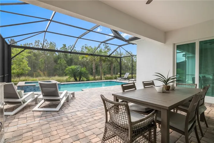 Outdoor pool featuring a jacuzzi, a patio area, glass enclosure, and outdoor dining area