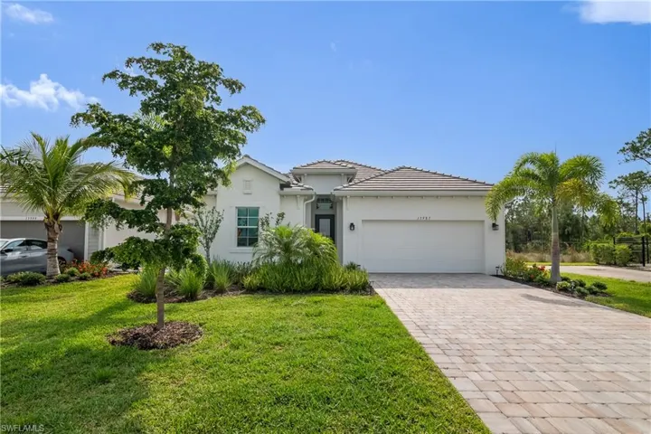 View of front of home featuring decorative driveway, a garage, stucco siding, and a front yard