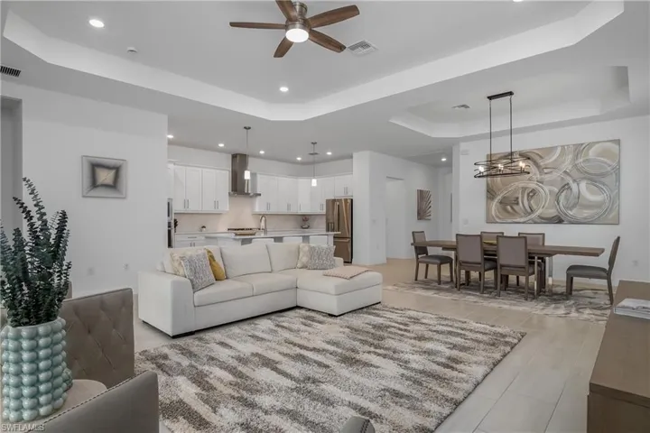 Living room featuring a tray ceiling, a ceiling fan, and recessed lighting