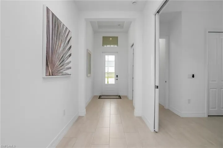 Entryway with a tray ceiling, baseboards, and light tile patterned floors