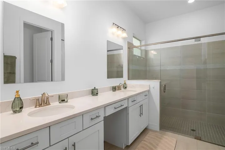 Full bathroom with double vanity, a stall shower, and tile patterned flooring
