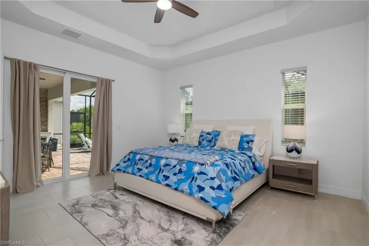 Bedroom with access to outside, a raised ceiling, ceiling fan, and baseboards